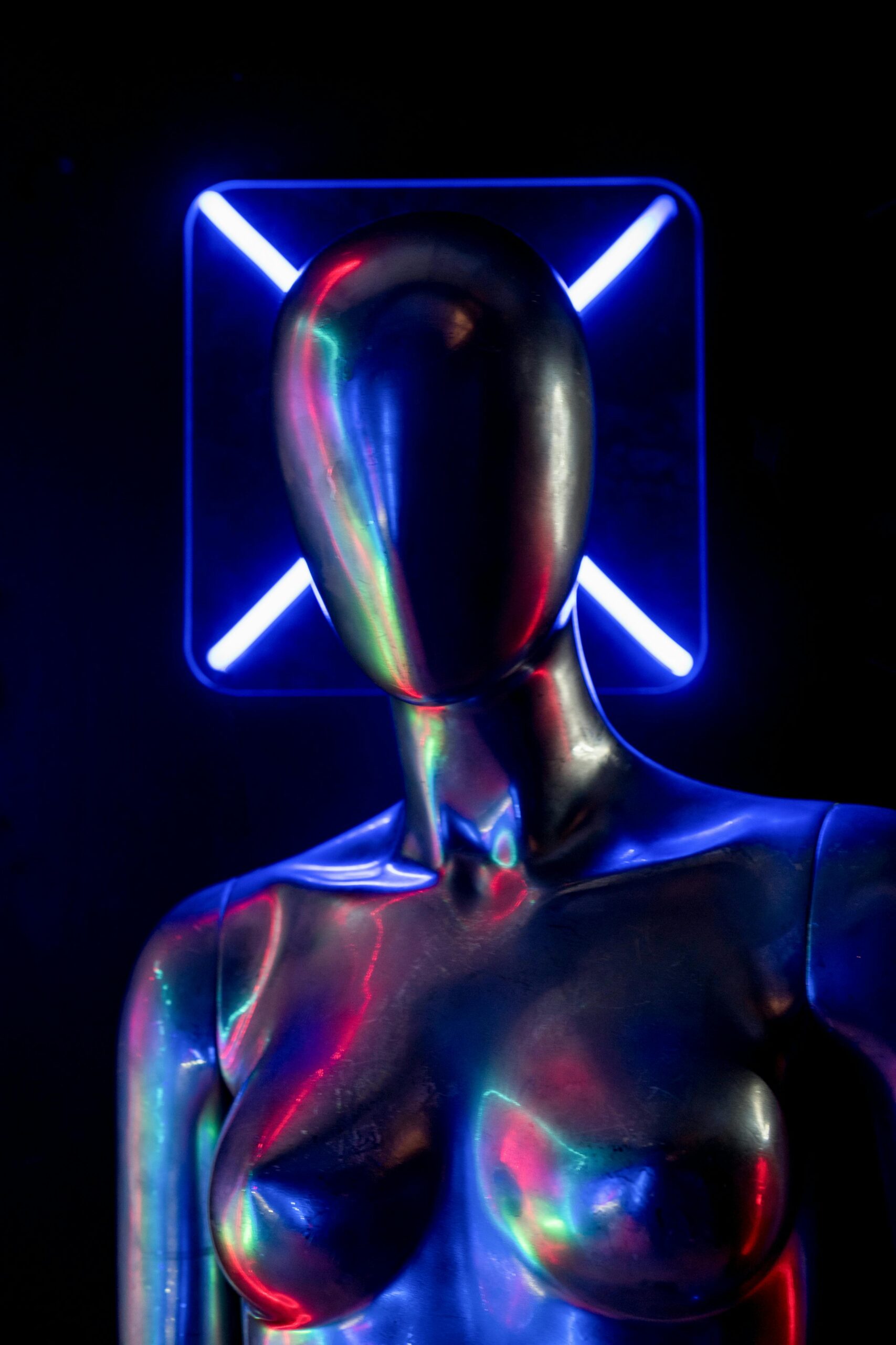 A metallic mannequin illuminated by vibrant neon blue lighting.